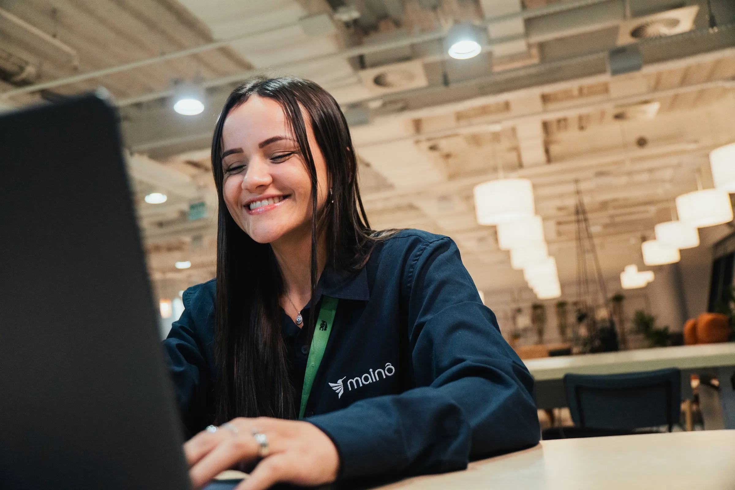 Colaboradora da Mainô sorrindo à mesa, no escritório