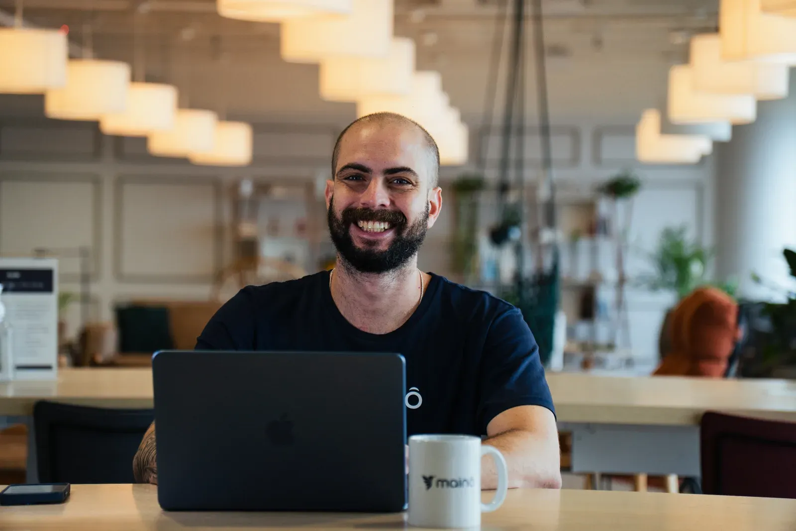 Colaborador da Mainô sorrindo diante do notebook no escritório