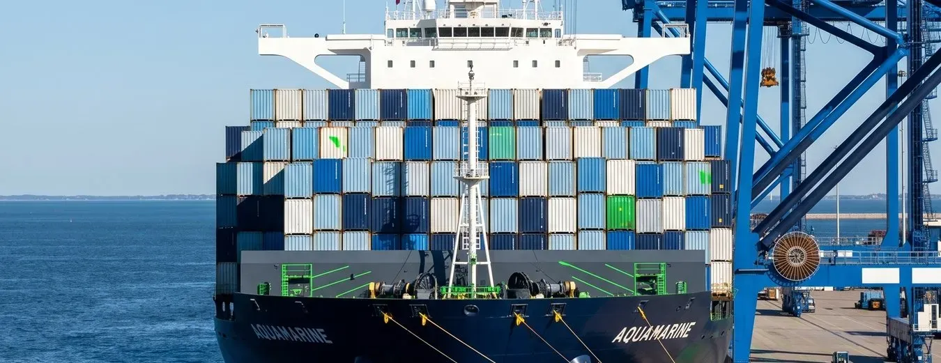 Navio carregado de contêineres atracado ao lado de guindastes de pórtico no porto