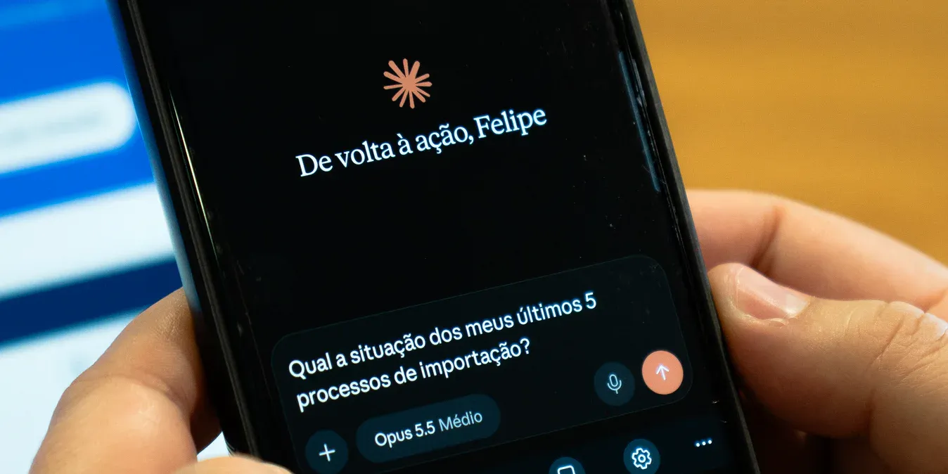 Mãos segurando um celular com um app de IA conectado à Mainô, onde a pessoa pergunta qual a situação dos seus últimos 5 processos de importação