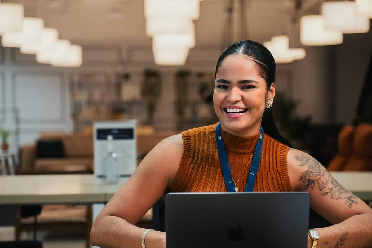 Colaboradora da Mainô sorrindo ao notebook no escritório