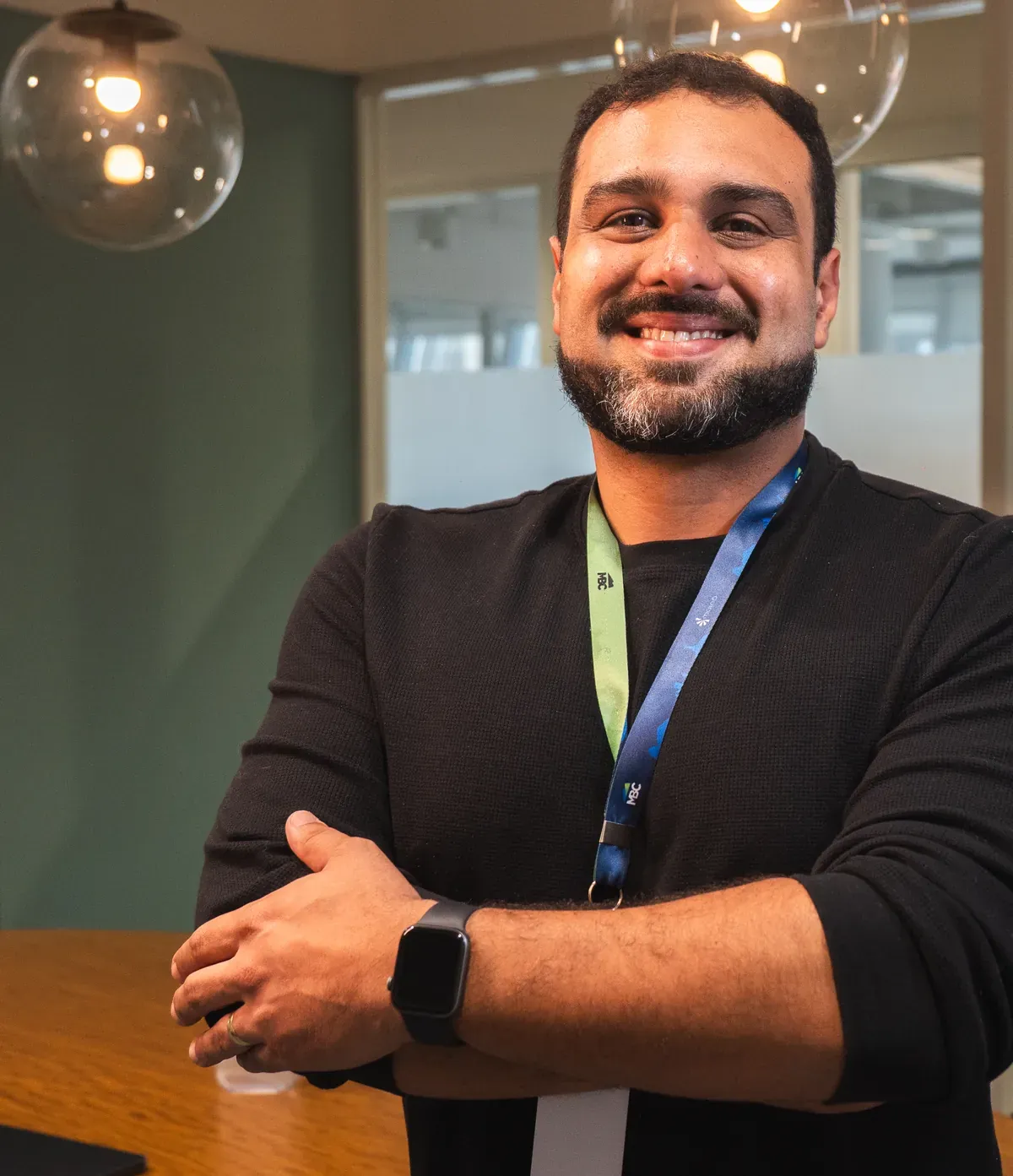 Colaborador da Mainô sorrindo, de braços cruzados, numa sala de reunião